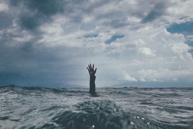 hand reaching up through surf